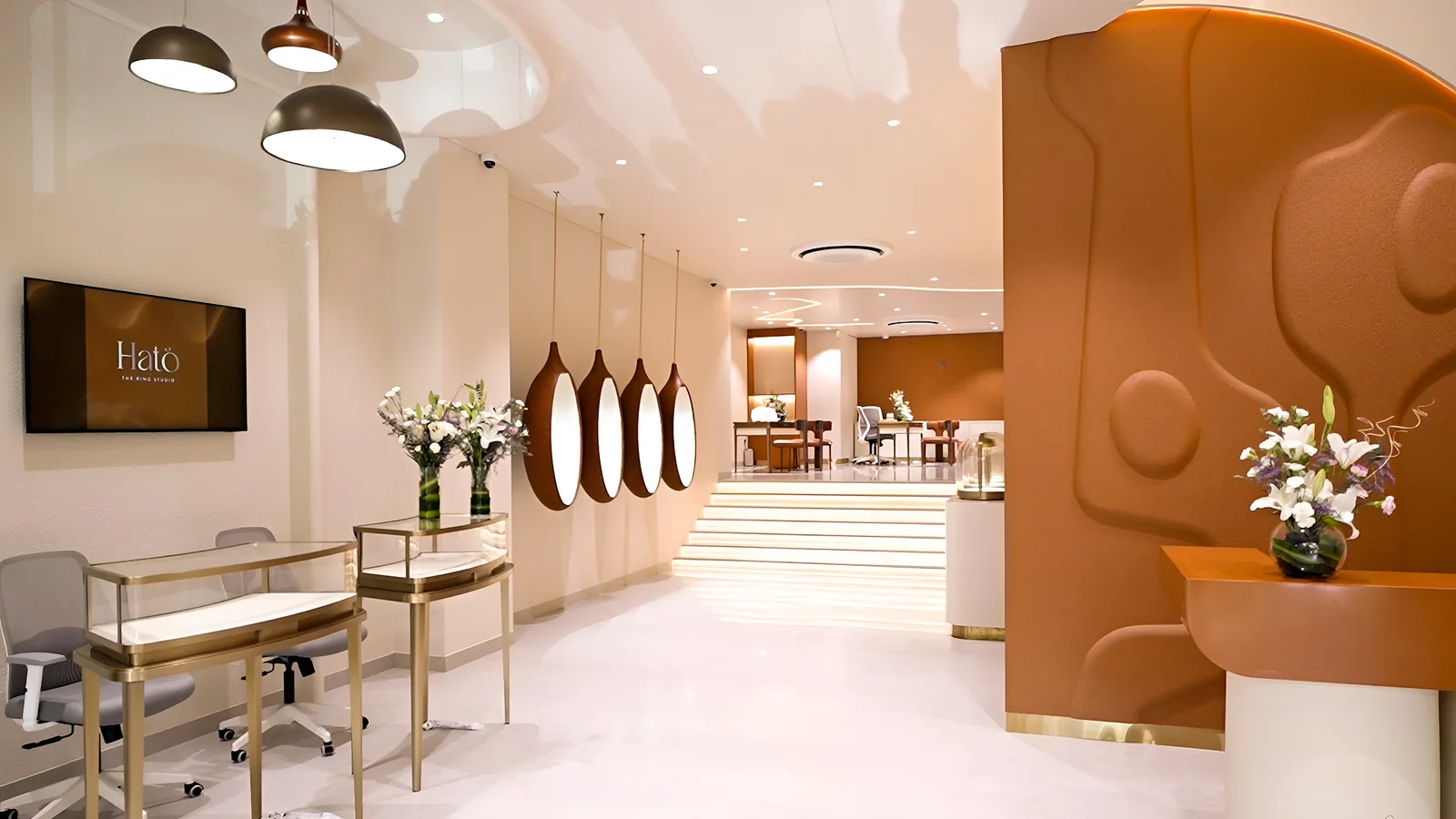 The HATO studio interior — sculpted terracotta wall, brass vitrines and a lit staircase